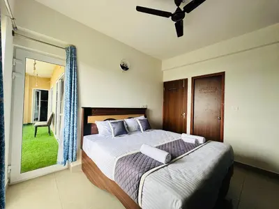 a bedroom with a bed and a window with a chair at Pearl Home Luxury 3Bhk family-friendly Appartment in Mysore