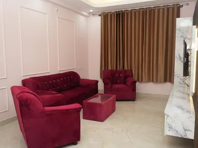 a living room with two red chairs and a couch at Serene Legacy in Mysore