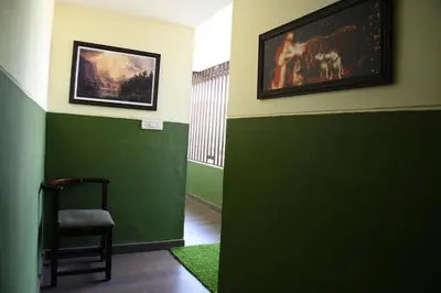 a green room with a chair and a painting on the wall at Athithi Comforts in Mysore