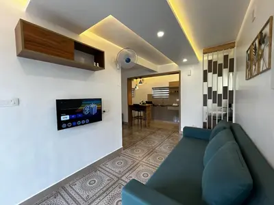 a living room with a couch and a tv on a wall at Vadanapilly Beach Villa for 8-10 adults in Irimbranallūr