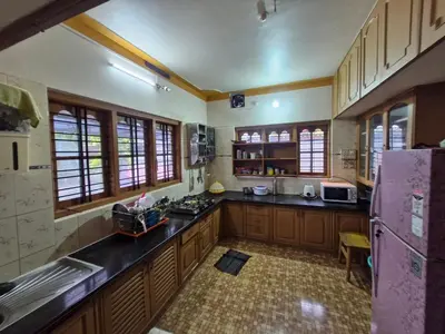 a large kitchen with wooden cabinets and a purple refrigerator at Coorg Coffee Tales in Suntikoppa