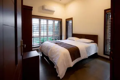 a bedroom with a bed and two windows at Thiraa Inn Nilambur By Hotelbuz in Nilambūr