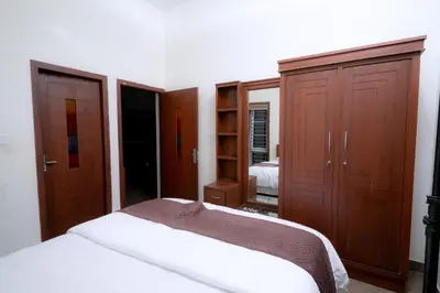 a bedroom with a bed and wooden cabinets at Thiraa Inn Nilambur By Hotelbuz in Nilambūr