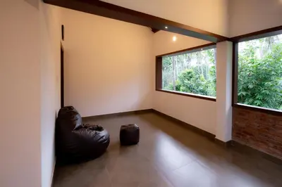 an empty room with a large window and a leather ottoman at Thiraa Inn Nilambur By Hotelbuz in Nilambūr