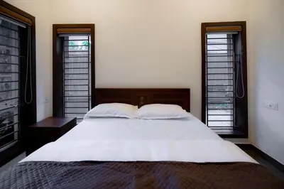 a bedroom with a large white bed with two windows at Thiraa Inn Nilambur By Hotelbuz in Nilambūr