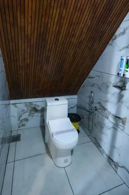 a bathroom with a toilet and a wooden ceiling at Heaven-Vadanapilly Beach Villa in Irimbranallūr