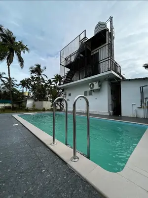 a swimming pool in front of a building at Heaven-Vadanapilly Beach Villa in Irimbranallūr