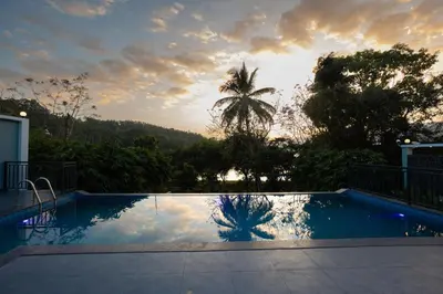 a swimming pool with the sunset in the background at Lake Paradise Resort in Padinjarathara