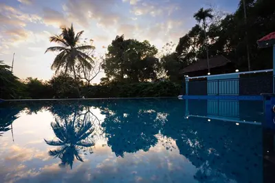 a reflection of a palm tree in a swimming pool at Lake Paradise Resort in Padinjarathara