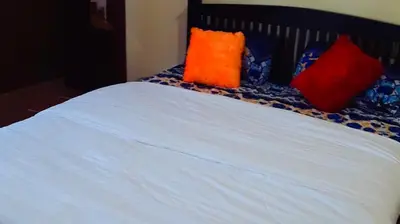a bed with red and orange pillows on it at 7th Heaven Kannur in Kannur