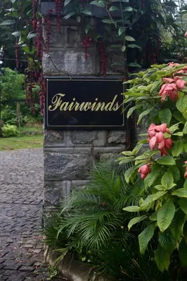 a sign on the side of a building with flowers at Fairwinds Coorg - Boutique Homestay at Coffee Farm in Virajpet