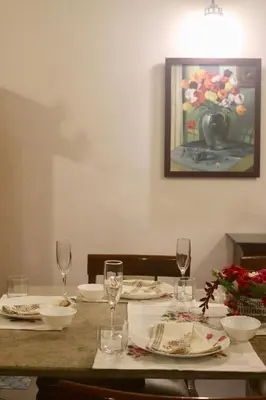 a table with plates and glasses and a painting on the wall at Fairwinds Coorg - Boutique Homestay at Coffee Farm in Virajpet