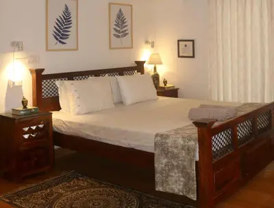 a bedroom with a large bed with white sheets at Fairwinds Coorg - Boutique Homestay at Coffee Farm in Virajpet