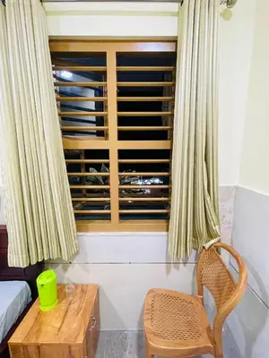 a room with a window with a chair and a table at Mp DREAMS ROOMS in Edappāl