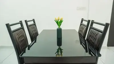 a glass table with a vase with flowers in it at Panakkal Homes in Guruvāyūr