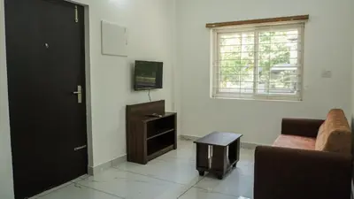 a living room with a couch and a table and a window at Panakkal Homes in Guruvāyūr