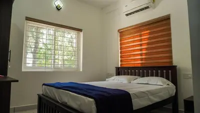 a bedroom with a bed and a window at Panakkal Homes in Guruvāyūr