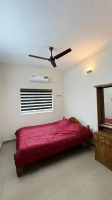a bedroom with a red bed and a ceiling fan at Chandras appartment in Palakkad