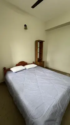 a bedroom with a large bed with a blue comforter at Chandras appartment in Palakkad