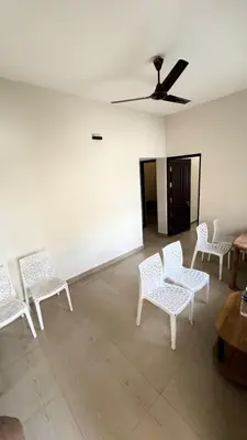 a room with white chairs and a ceiling fan at Chandras appartment in Palakkad