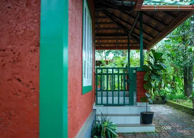 a red and green building with a window and a porch at Paddy Land in Wayanad