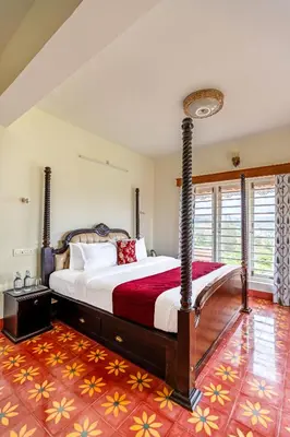 a bedroom with a large bed with a red blanket at Mihirika's Nirvana 5-BHK With Garden, Gazebo, Bonfire Pit & Scenic Views in Ooty