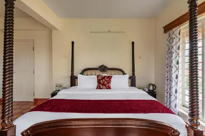a bedroom with a large bed with a red blanket at Mihirika's Nirvana 5-BHK With Garden, Gazebo, Bonfire Pit & Scenic Views in Ooty