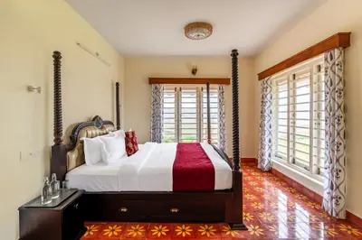 a bedroom with a bed in a room with windows at Mihirika's Nirvana 5-BHK With Garden, Gazebo, Bonfire Pit & Scenic Views in Ooty