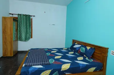 a bedroom with a bed with a blue comforter at 2Bhk White House Near Isha By Shivalaya Stays in Coimbatore