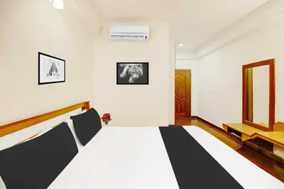 a bedroom with a black and white bed and a window at Super Townhouse Oak Mysuru City Bus Terminal in Mysore