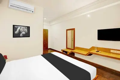 a bedroom with a bed and a flat screen tv at Super Townhouse Oak Mysuru City Bus Terminal in Mysore