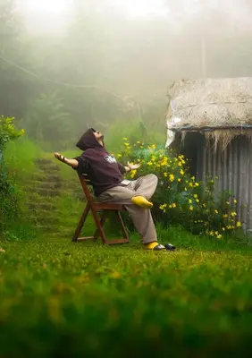a man sitting in a chair in the grass at Elim Retreat kanthalloor in Kanthalloor