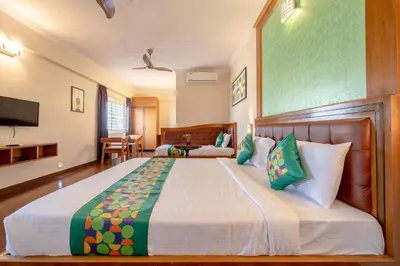 a bedroom with a large bed with green and white pillows at Treebo Akshaya Palace Inn in Mysore