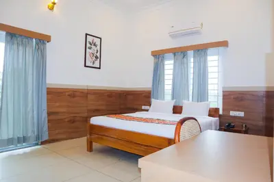 a bedroom with a bed and two windows and a table at Sonam hotel and restaurant in Kushālnagar