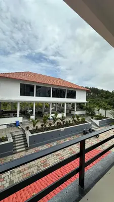 a large white building with palm trees in front of it at Sonam hotel and restaurant in Kushālnagar