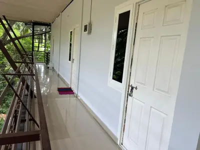 a hallway with a white door and a staircase at Mundodan complex in Nilambūr