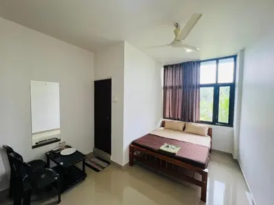 a bedroom with a bed and a window and a chair at Mundodan complex in Nilambūr