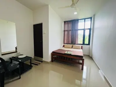 a room with a bed and a chair and a window at Mundodan complex in Nilambūr