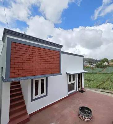 a house with a large red brick wall at SRB Cottages in Ooty