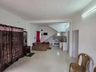 a living room with a couch and a kitchen at SRB Cottages in Ooty