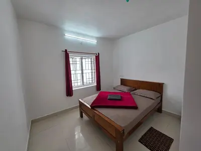 a room with a bed with a red blanket on it at SRB Cottages in Ooty