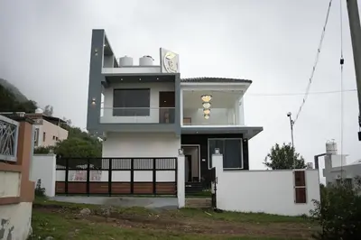 a large white house with a fence in front of it at Vaj N Sat Villas in Kodaikānāl
