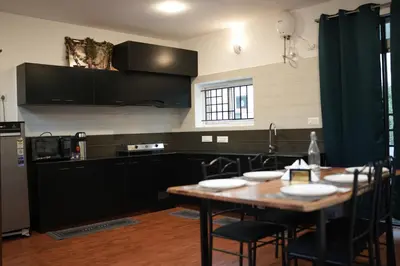 a kitchen with a wooden table and black cabinets at Vaj N Sat Villas in Kodaikānāl