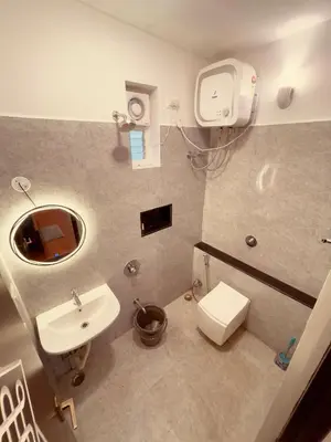 a bathroom with a sink and a toilet and a mirror at Vaj N Sat Villas in Kodaikānāl