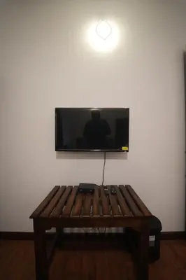 a flat screen tv on a wall with a wooden table at Vaj N Sat Villas in Kodaikānāl
