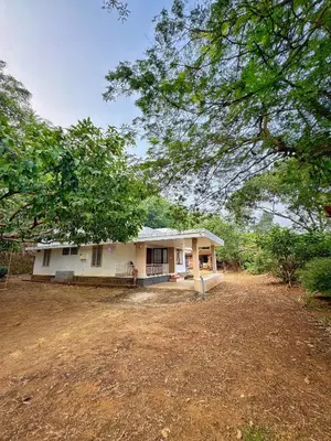 a white house with a tree in front of it at Maanasam Farmstay - Boutique 3BR Countryside Villa, Manikkadavu in Irrity