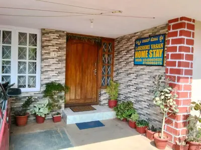 a brick house with a wooden door and a sign at Lakshmi Vasan Homestay in Madikeri