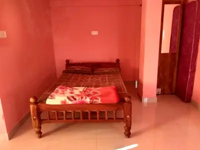 a bedroom with a bed with a red pillow on it at Lakshmi Vasan Homestay in Madikeri