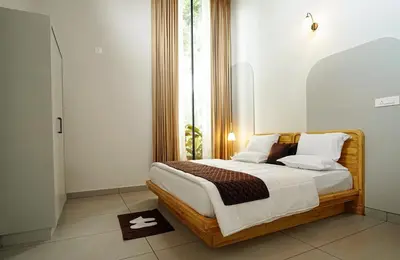 a bedroom with a bed with a large window at wayanadjunglevillas in Kenichira