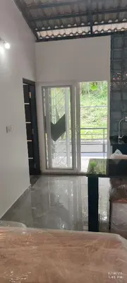 an empty room with a large glass door and a window at Tusker villa in Suntikoppa